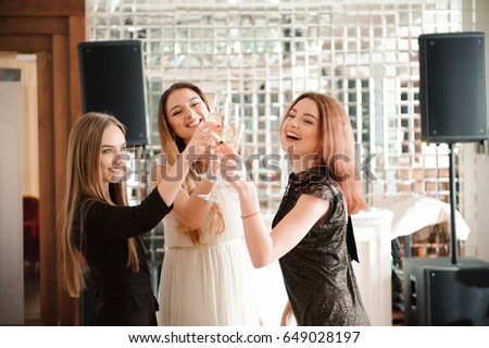 Portrait of smiling friends holding glass of champagne while dancing at bar