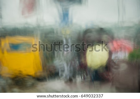 Rainy day abstract weather photo trough wet window. rain street view and traffic. Bus station and crowd of people. 