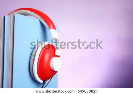 Headphones and books on color background. Concept of audiobook
