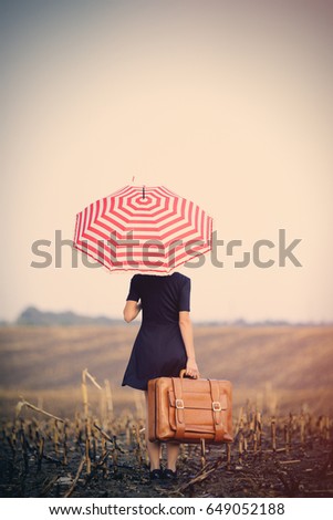 photo of beautiful young woman with suitcase and umbrella on the wonderful field and sky background
