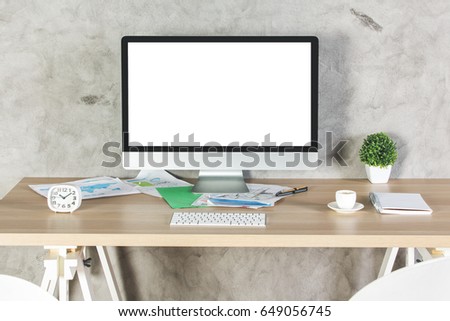 Front view of creative office desktop with empty white pc, drink, supplies and other items on concrete wall background. Mock up