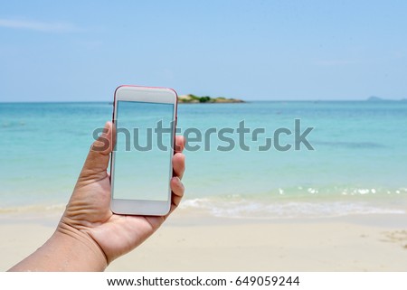 hand hold and touch screen smart phone,cellphone over blurred beautiful beach background abstract background for working on Summer Vacation.