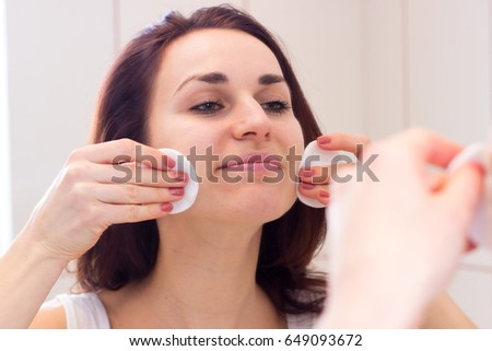 Young woman removing makeup in bathroom