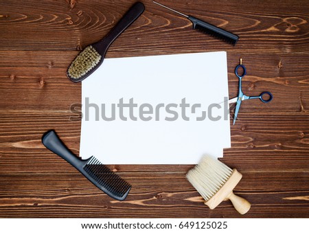 Hairdresser tools on wooden background. Blank card with barber tools flat lay. Top view on wooden table with scissors, comb and brush with empty white paper, free space
