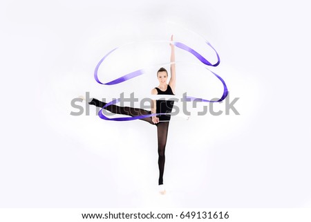Smiling young rhythmic gymnast exercising with ribbon and looking at camera 