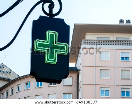 Neon generic sign drugstore pharmacy pharmacie with apartment building in the background in French city
