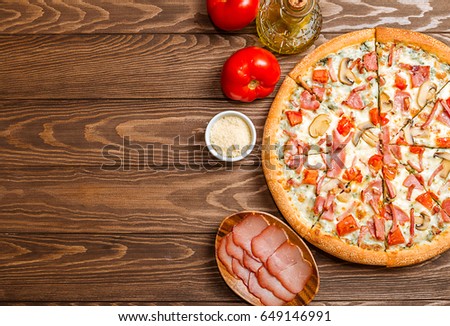 Delicious pizza with mushrooms and ham served on wooden table, top view