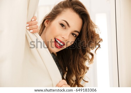 Picture of happy young lady standing in fitting room. Looking at camera.