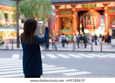 Female asian tourist using smartphone for taking photo of giant lantern at Sensoji Shrine (temple), Asakusa, Tokyo, Japan.