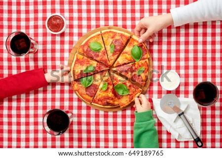 Family in italian national colors clothes taking pieces of pizza, top view