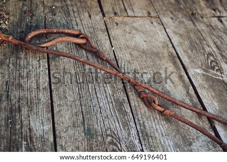 Rusty metal shackle on a metal bar laying on weathered wood outdoors