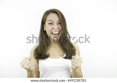 Surprise and show fists with happy smiling face in white casual dress, posing by asian woman at studio, isolated grey background.