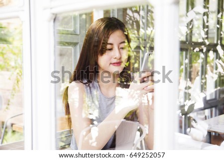 Asian women use smartphone in cafe shop.