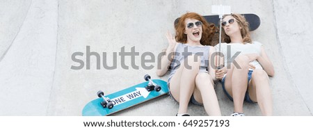 Joyful skate girls taking a selfie with skateboards