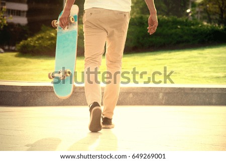 Guy with a skateboard strolls in a park under the scorching sunlight