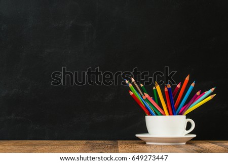 back to school learning concept with white coffee cup group, lots of rainbow pencils in classroom, blackboard wall background on wood desk.