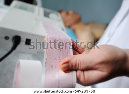 Electrocardiogram, ecg in hand. Clinic cardiology heart rhythm and pulse test closeup. Cardiogram printout. Royalty-Free Stock Photo #649283758
