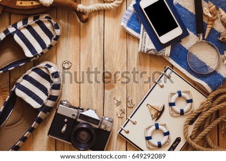Striped slippers, camera and maritime decorations on the wooden background, top view