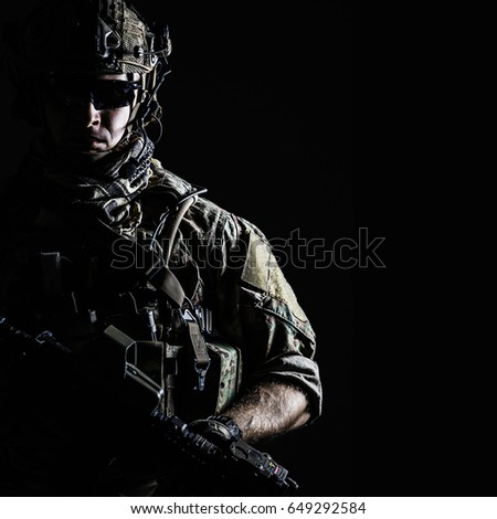 Elite member of US Army rangers in combat helmet and dark glasses. Studio shot, dark black background, looking at camera, dark contrast