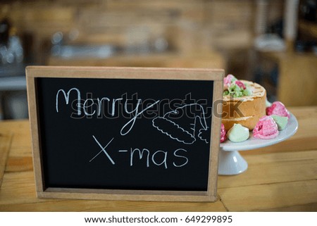 Merry x mas sign board with cake at counter in cafÃ©