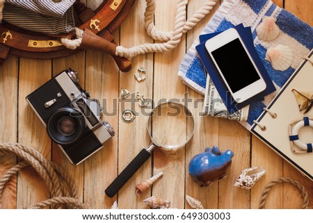 Striped towel, piggy bank, phone and maritime decorations on the wooden background, top view