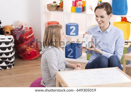 Child counselor showing drawings to little smart girl with ADHD