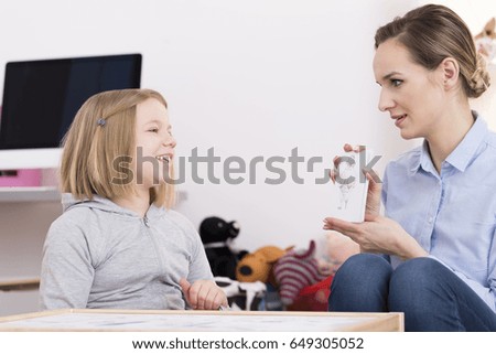 Child counselor discussing drawing with smiling girl during play therapy