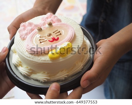 Hand is holding a rabbit cartoon cake to send together.