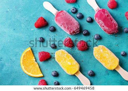 Home made ice cream with berries, orange over blue wooden background. Top view
