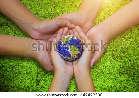 Earth planet in asian Children hand on green grass background. - Elements of this image furnished by NASA Royalty-Free Stock Photo #649492300