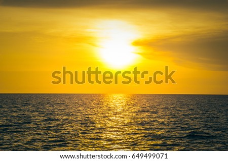 Beautiful blazing sunset landscape at black sea and orange sky above it with awesome sun golden reflection on calm waves as a background. Amazing summer sunset view on the beach.