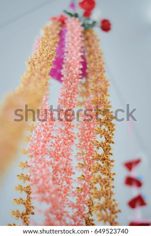 Bunch of small flowers hanging upside down on a string.Handmade work for interior decoration for home and office.Threads background,Beautiful designs come from many different colors.