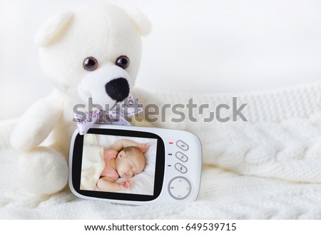 baby monitor for security of the baby surrounded by a teddy bear on a light background. close-up Royalty-Free Stock Photo #649539715