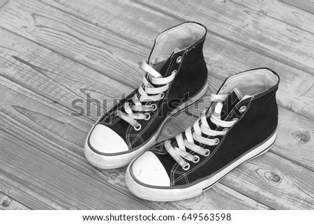 Monochrome black and white grunge wooden background with vintage canvas sneakers