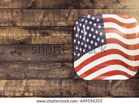 Paper plate with american flag on the wooden table.
