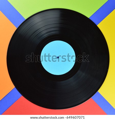 old black vinyl record with blank cyan label centered on multicolored background in a square