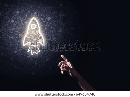Rocket glowing icon and man hand on dark background