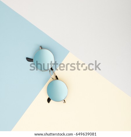 Minimal style. Minimalist Fashion photography. Fashion summer is coming concept. Blue glasses on a blue background, top view. Trendy minimal style with colorful paper backdrop