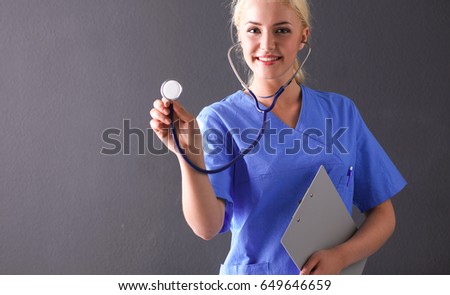 Female doctor with a stethoscope listening, isolated on gray background