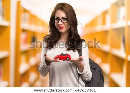 Student woman holding little car in a library