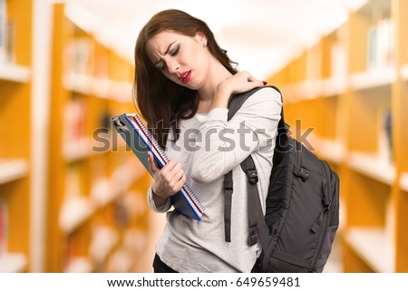 Student woman with neck pain in a library