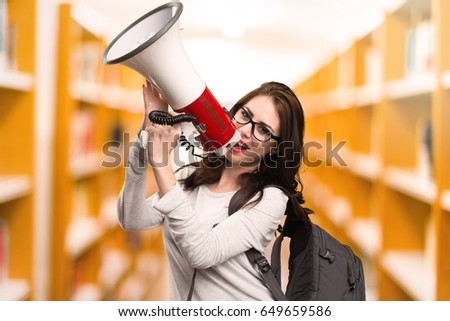 Student woman shouting by megaphone in a library