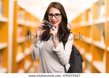 Student woman holding a camera in a library