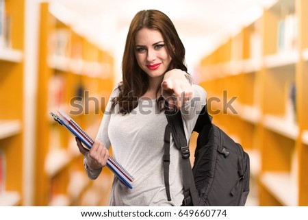 Student woman pointing to the front in a library