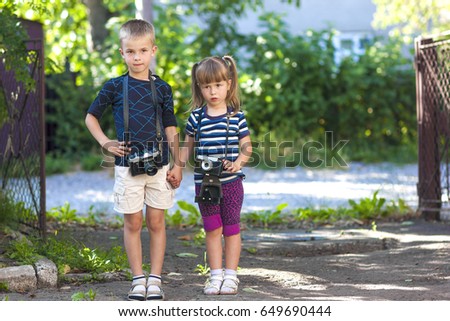 Little boy and a little girl wit two vintage cameras standing together holding hands