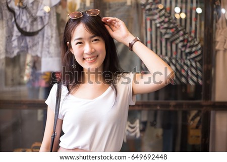 Young beautiful and pretty Asian woman with perfect smiling looking to the camera while put her sunglasses on her head