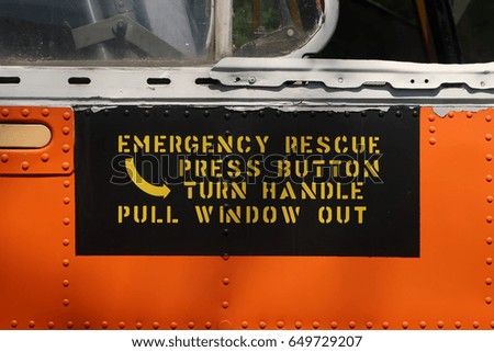 Sign that says, "EMERGENCY RESCUE PRESS BUTTON TURN HANDLE PULL WINDOW OUT.
