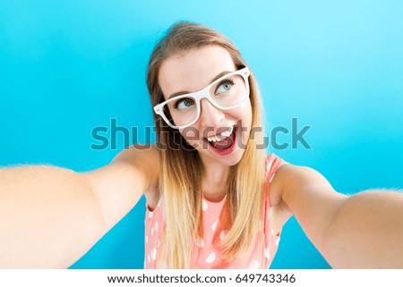 Young woman taking a selfie on blue background