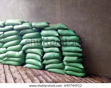 Green sandbag, flooded, placed next to the old wall.