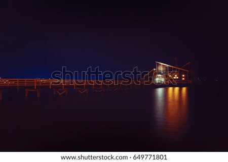 House on water at night. pier and a house by the sea
